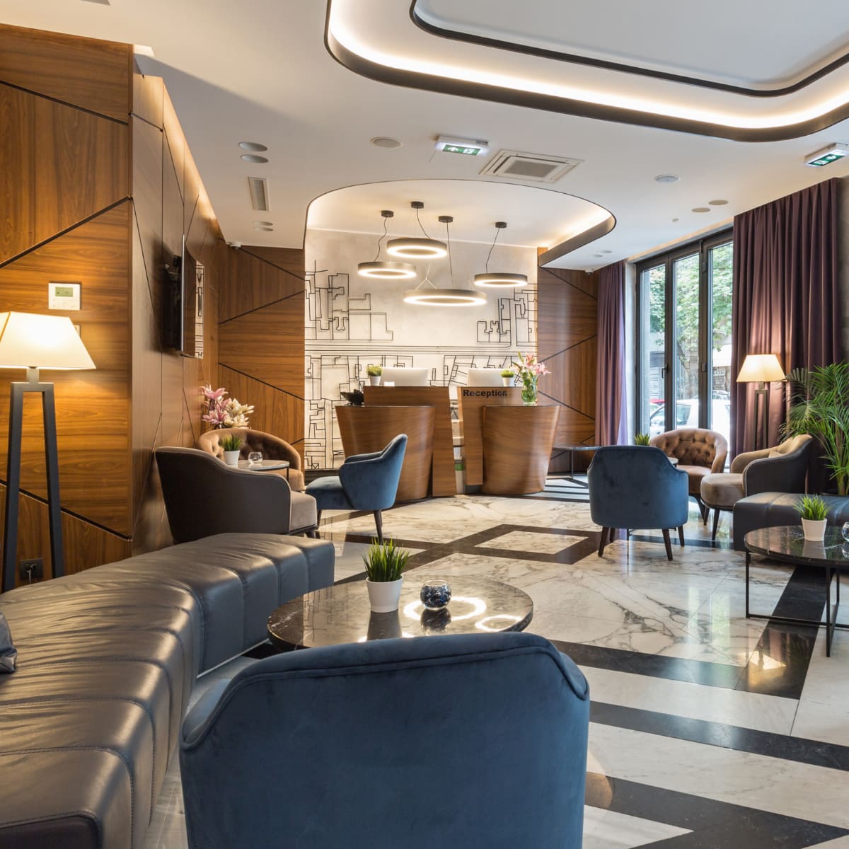 high end hotel lobby with reception desks, chairs, tables, and stylish lamps